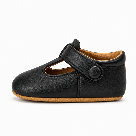Mocassin bébé noir à bride scratch - vue de profil. Maintien confortable, semelle souple camel et finition effet cuir grainé.