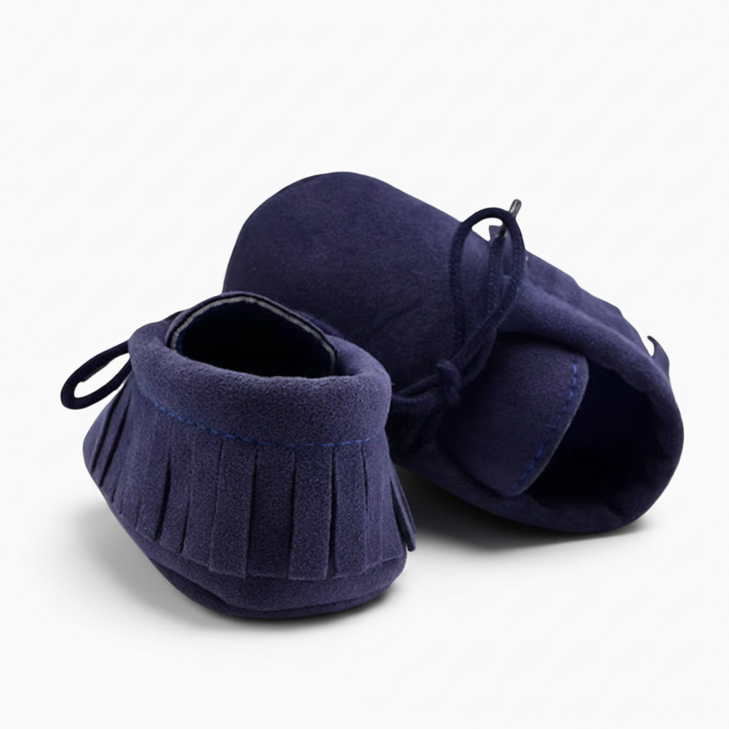 Gros plan sur la texture veloutée du daim bleu marine du mocassin, gage de douceur et de confort pour bébé.