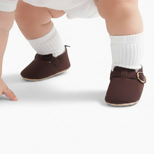Bébé faisant ses premiers pas, porté par le confort et le style de ses mocassins marron.