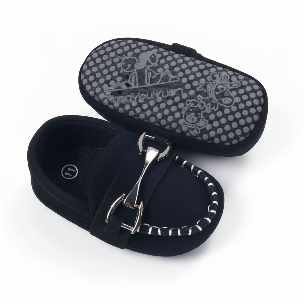 Bébé assis, pieds chaussés de mocassins noirs raffinés, complétant une tenue chic.