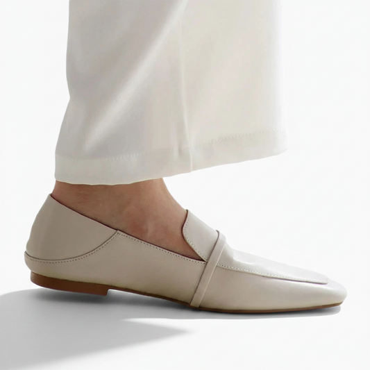 Pieds vêtus de mocassins crème, associés à un pantalon de tailleur clair pour un look de bureau sophistiqué.