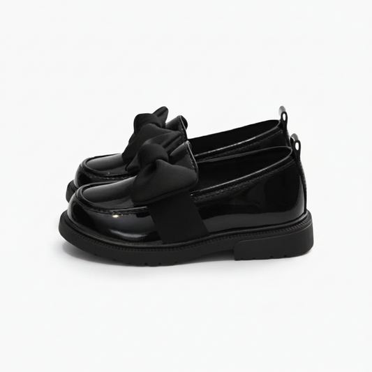 Vue de dessus d'un mocassin verni noir, mettant en valeur son délicat nœud papillon.