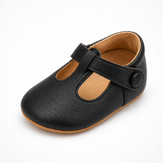 Mocassin bébé noir à bride scratch - vue trois-quarts. Chaussure souple premiers pas avec doublure camel, bouton latéral et semelle flexible.