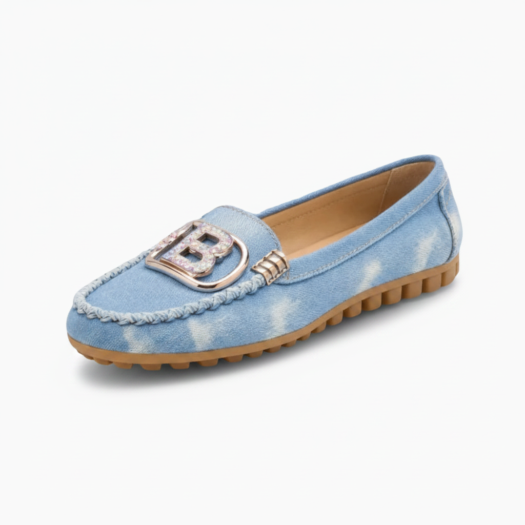 Mocassins en jean bleu pour femme, ornés de bijoux élégants, portés avec style sur un trottoir urbain.