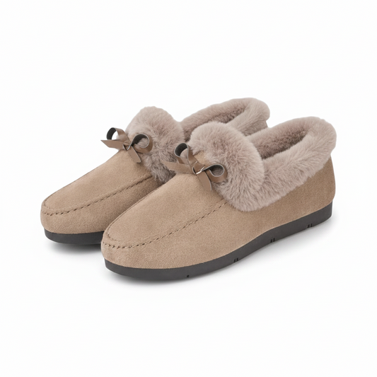 Paire de chaussons mocassins beiges pour femme, posée sur un tapis moelleux, invitant à la détente.