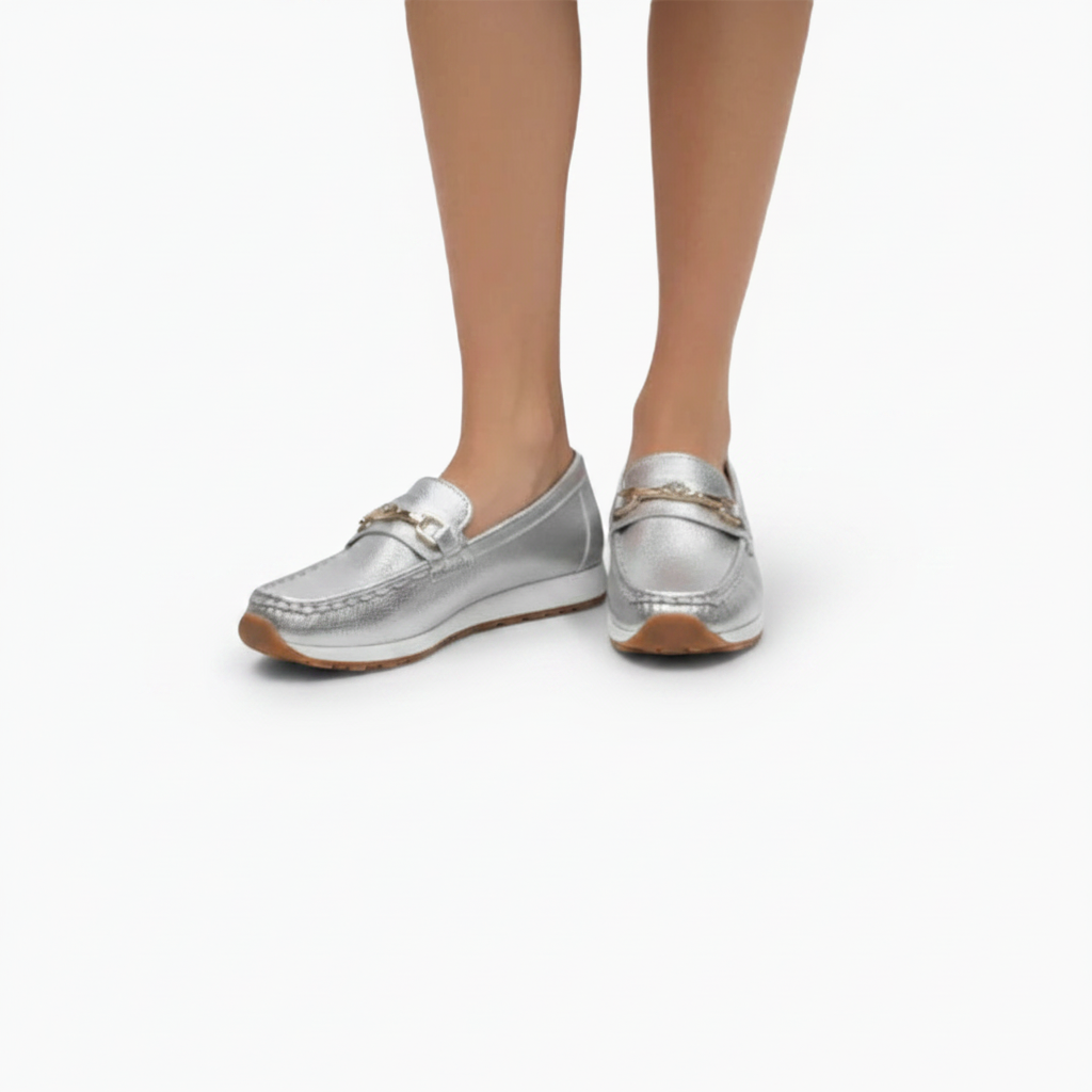 Paire de mocassins argentés posée sur un fond neutre, mettant en valeur leur brillance unique.
