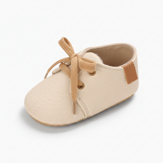 Mocassin bébé beige en cuir souple avec lacets ajustables pour premiers pas.