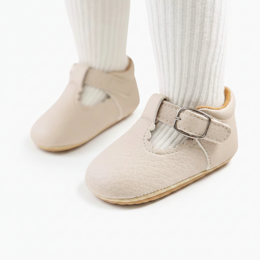 Paire de mocassins bébés en cuir beige, élégance naturelle, capturée d'en haut sur fond clair.