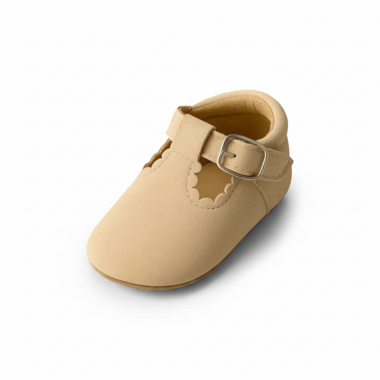 Mocassins beige doux aux pieds d'un bébé explorant en rampant sur un tapis douillet.