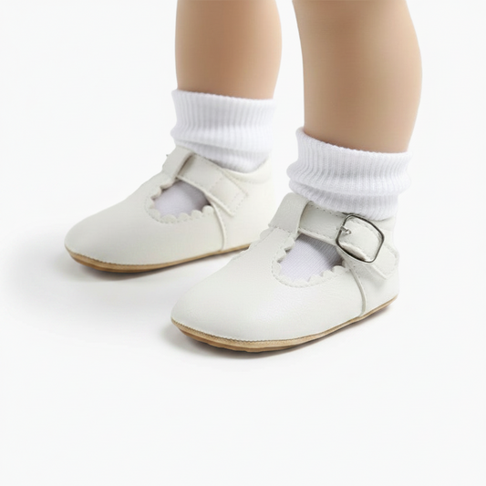 Vue de côté d'un mocassin bébé blanc, mettant en valeur sa semelle souple pour l'apprentissage de la marche.
