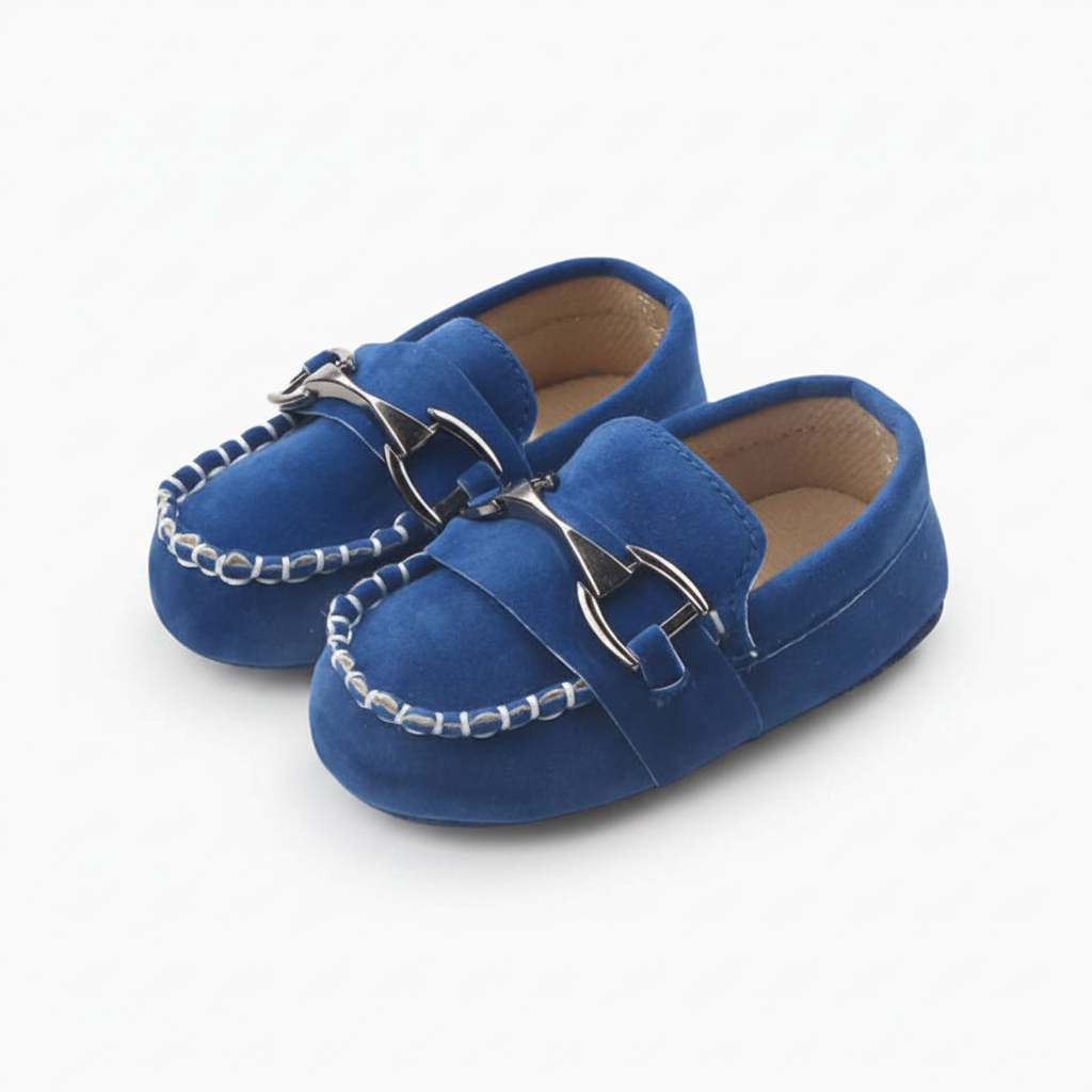Mocassins bébé bleus élégants avec chaînette dorée, soutenant les premiers pas d'un enfant en bas âge.