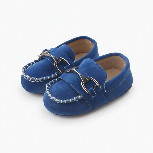 Mocassins bébé bleus élégants avec chaînette dorée, soutenant les premiers pas d'un enfant en bas âge.