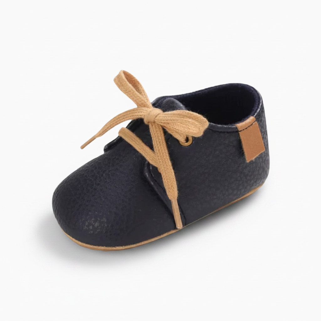 Mocassins bébé bleu marine en cuir souple, parfaits pour les premiers pas élégants et confortables.