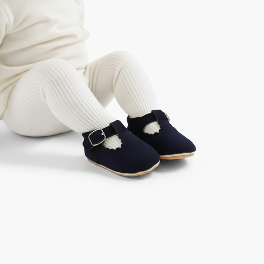 Bébé souriant, découvrant le monde avec ses doux mocassins bleu marine aux pieds.