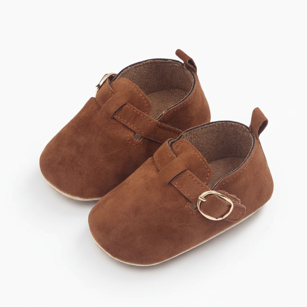 Bébé faisant ses premiers pas, chaussé de mocassins en daim marron, assurant un bon maintien et souplesse.
