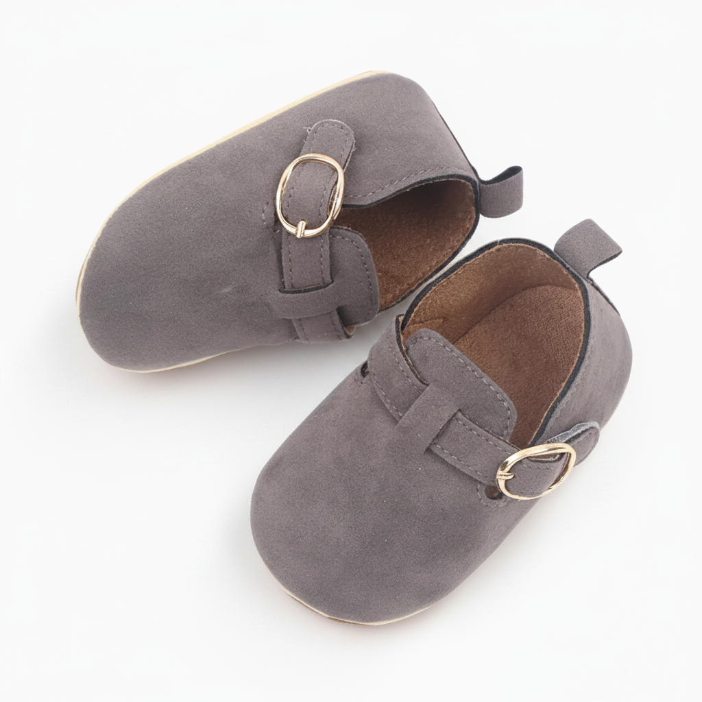 Bébé explorant doucement le monde, chaussé de ses élégants mocassins gris en daim, vue de profil.
