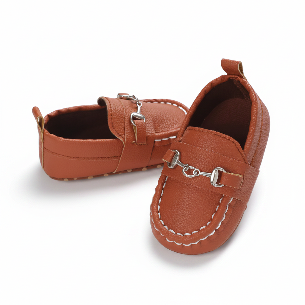 Mocassins bébé marron à chaînette présentés dans un écrin, une idée cadeau parfaite et raffinée pour nouveau-nés.