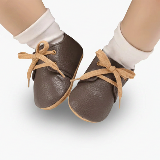 Mocassins bébé marron foncé vus de profil, mettant en avant la semelle antidérapante en caoutchouc.
