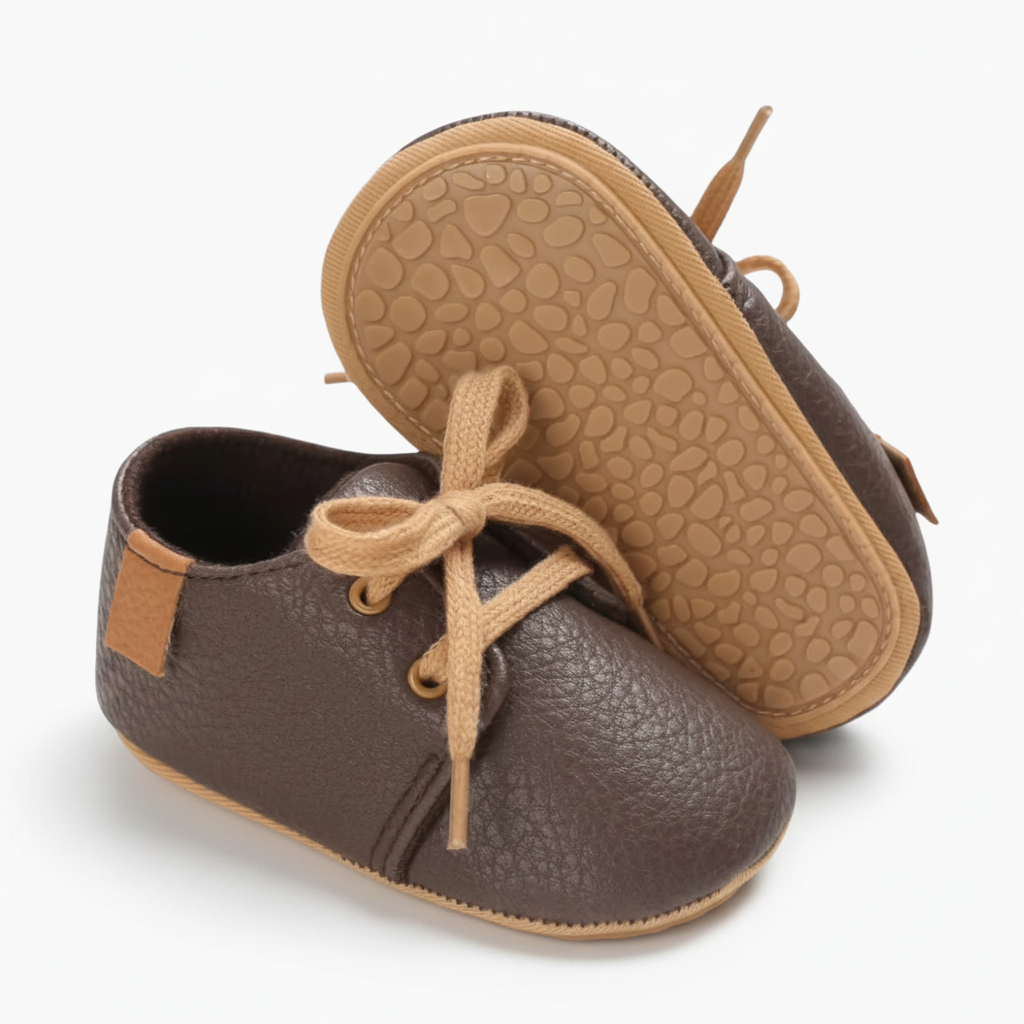 Un bébé souriant explorant le sol, chaussé des mocassins en cuir marron, garantissant un bon maintien.