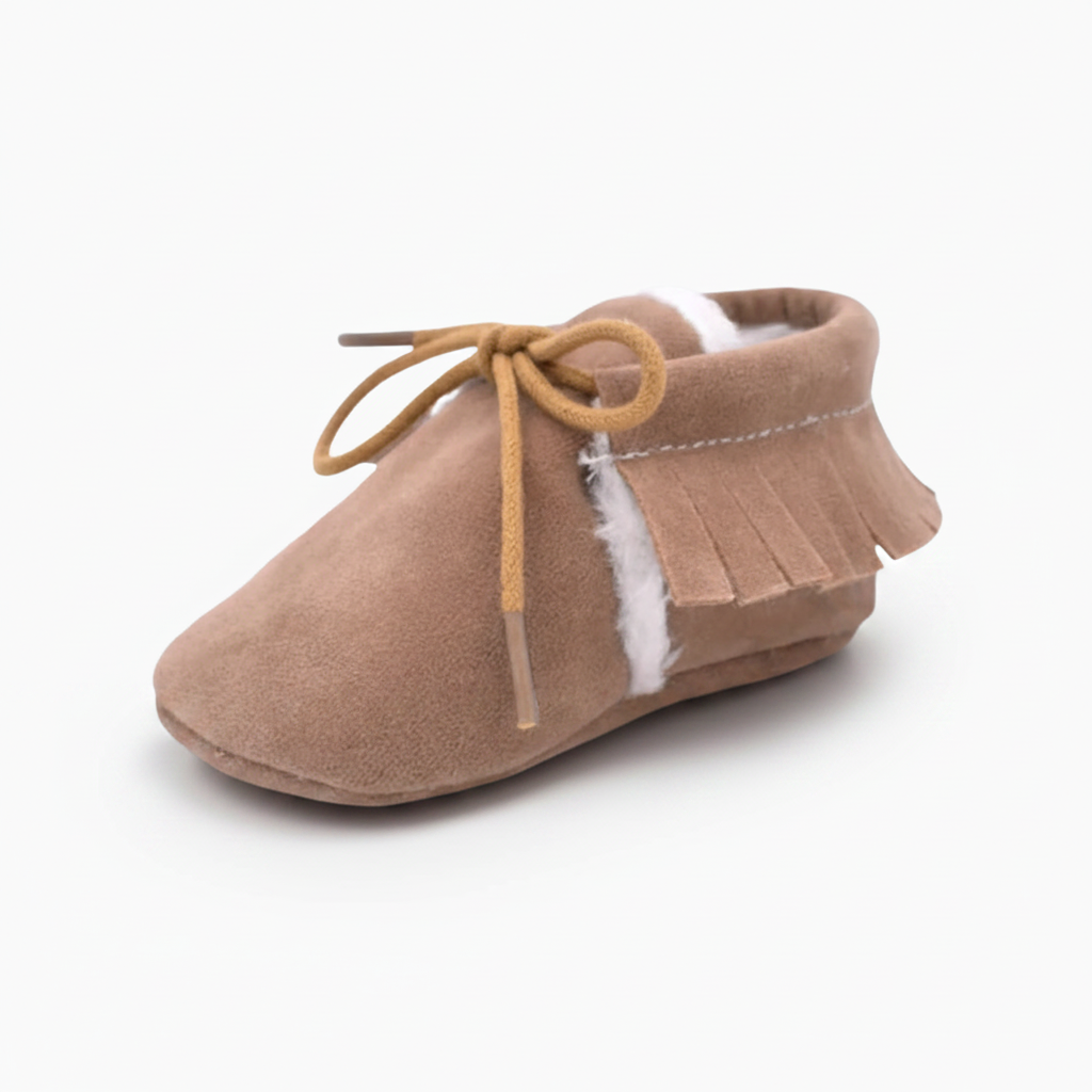 Vue rapprochée du cuir souple marron et des coutures délicates du mocassin bébé, signe de qualité.