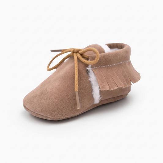 Vue rapprochée du cuir souple marron et des coutures délicates du mocassin bébé, signe de qualité.