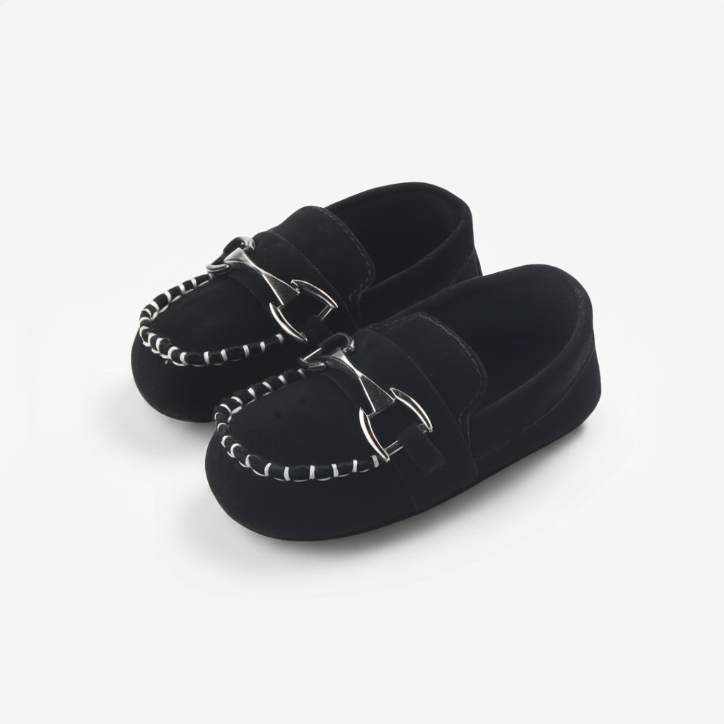 Premiers pas d'un enfant avec des mocassins noirs à chaînette, offrant style et soutien.