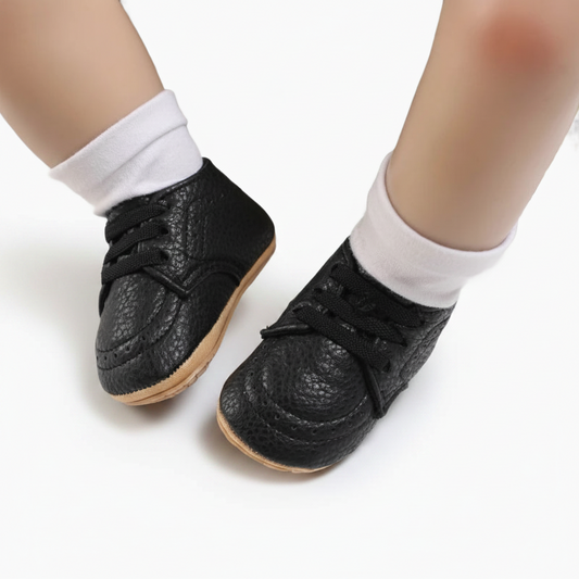 Vue détaillée du lacet ajustable et du design intemporel du mocassin bébé noir en matière souple.