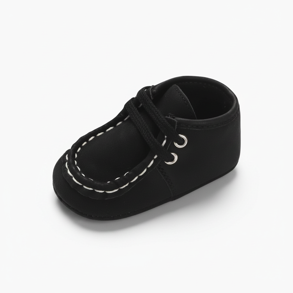 Mocassin bébé noir en daim avec détails blancs, idéal pour les premiers pas élégants.