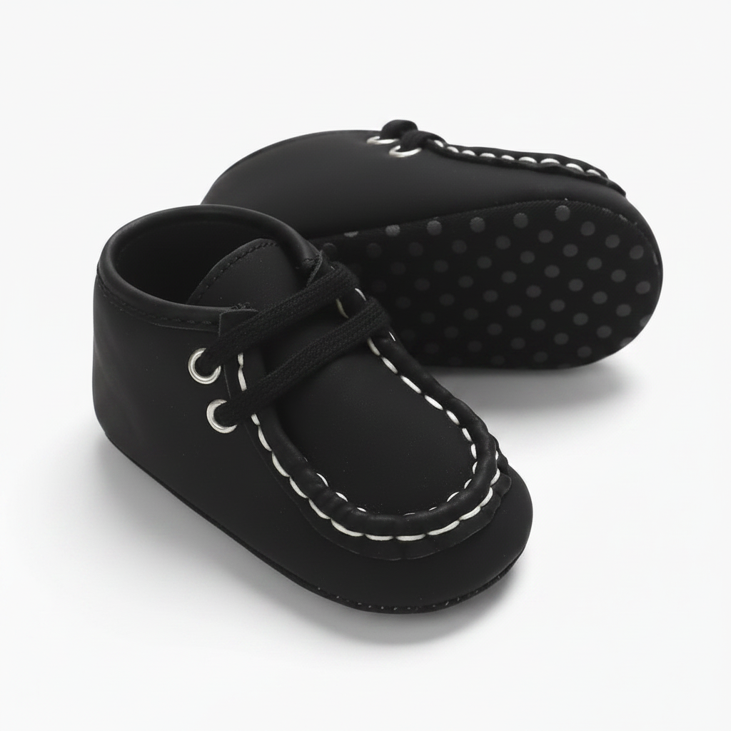 Paire de mocassins bébé noirs au design sophistiqué, avec leurs détails blancs distinctifs.