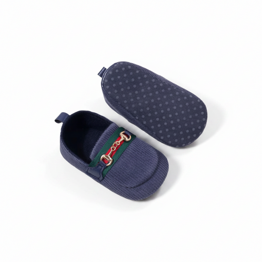 Mocassin bébé bleu marine sur une surface douce, mettant en valeur son design raffiné et intemporel.