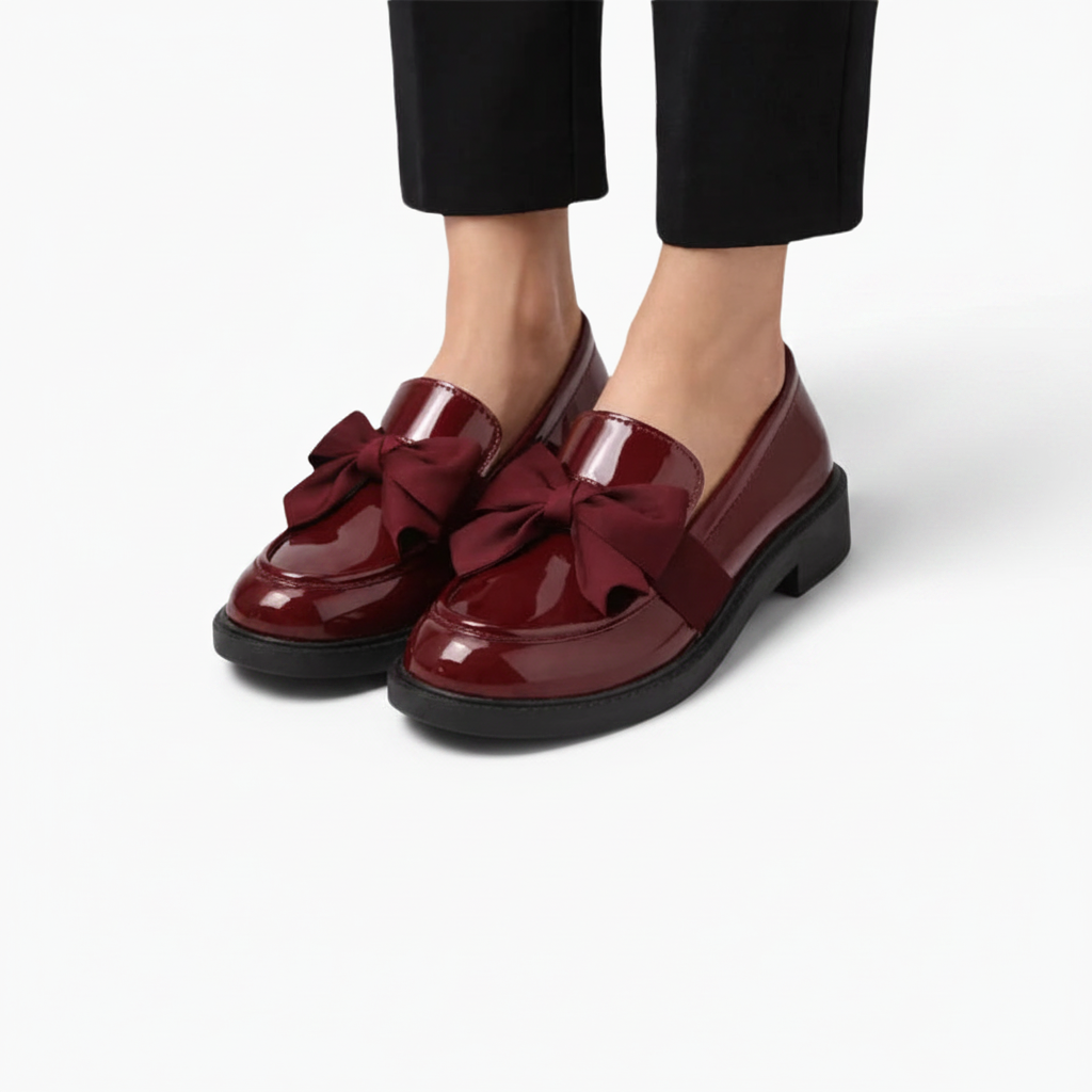 Paire de mocassins vernis bordeaux posés de côté, révélant leur ligne épurée et leur éclat subtil.