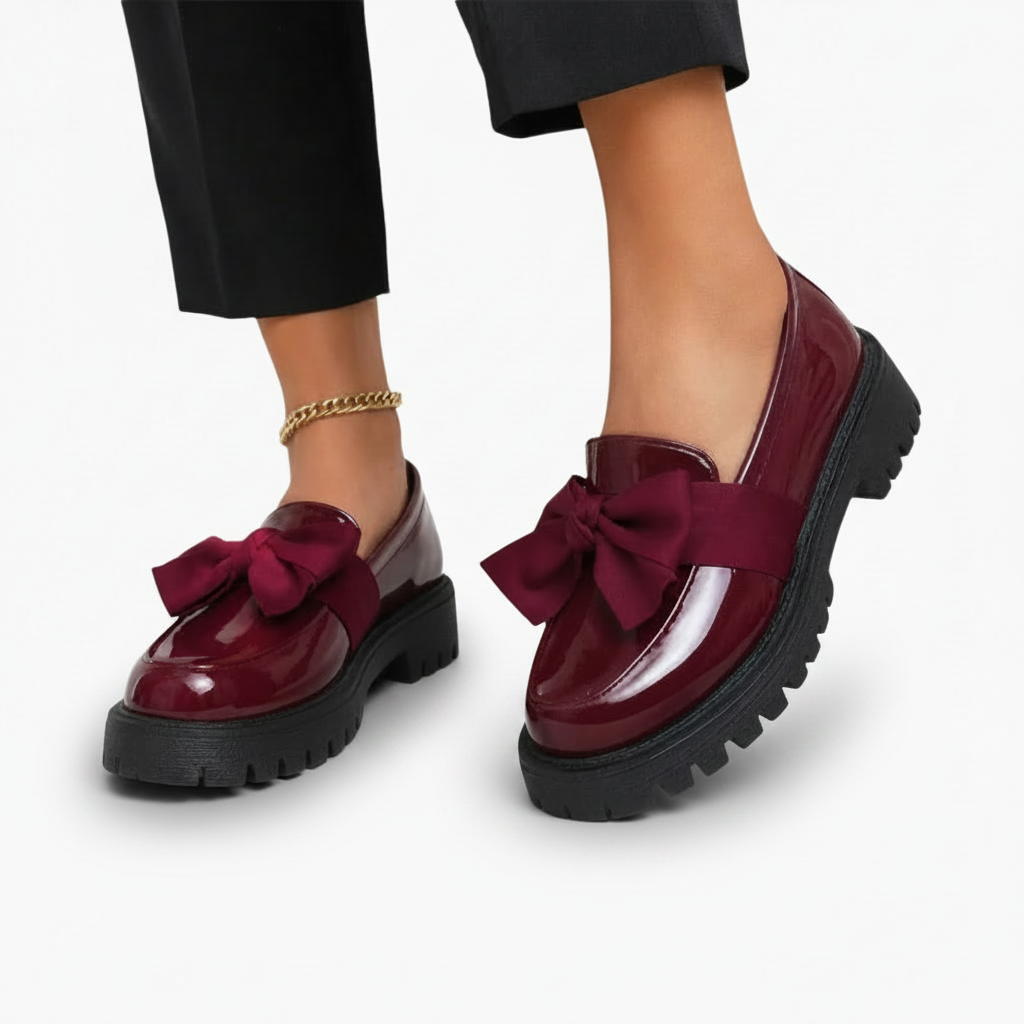 Paire de mocassins compensés bordeaux vernis portés, apportant une touche d'élégance affirmée à la silhouette.