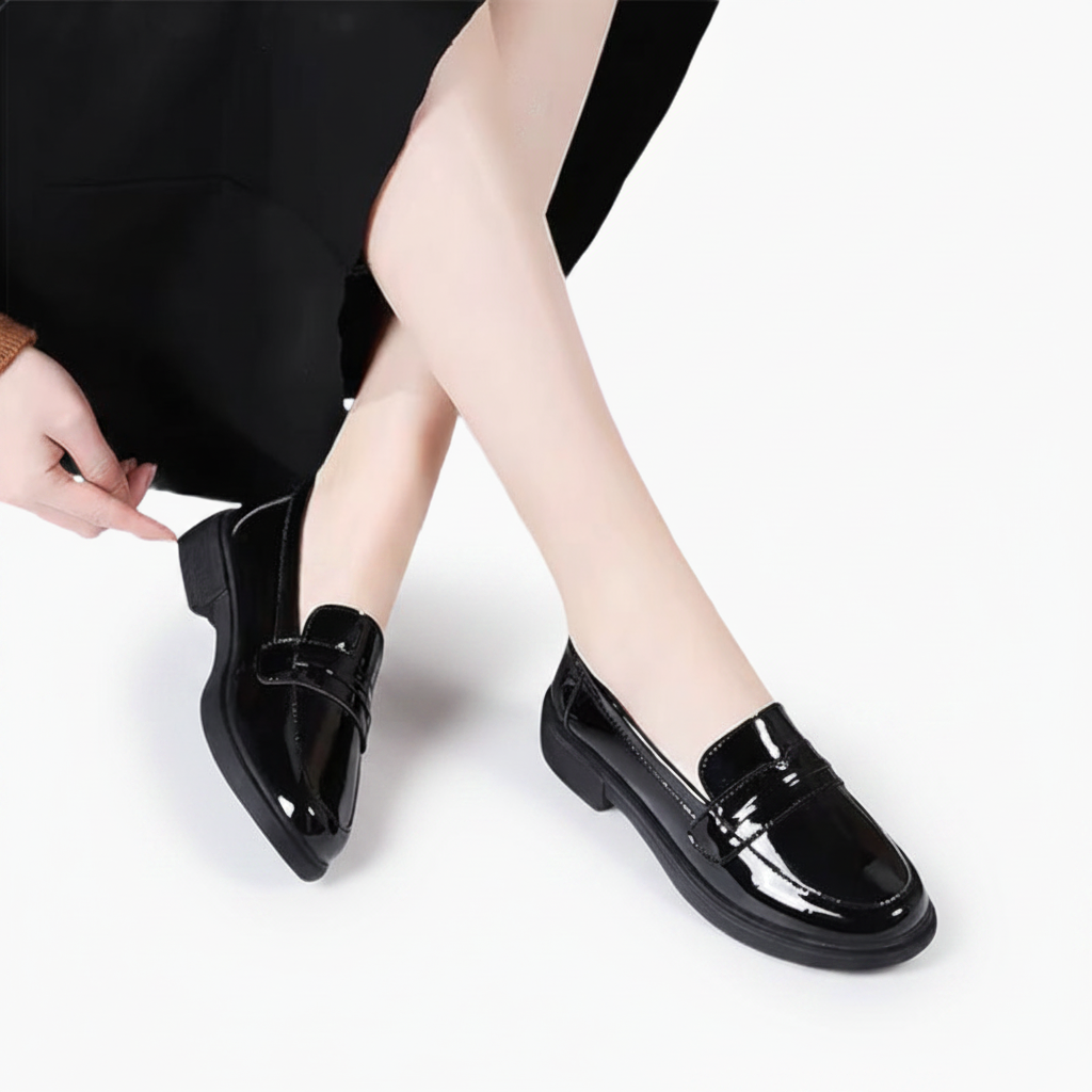 Pied féminin portant un mocassin compensé cuir noir, marchant avec style en ville.