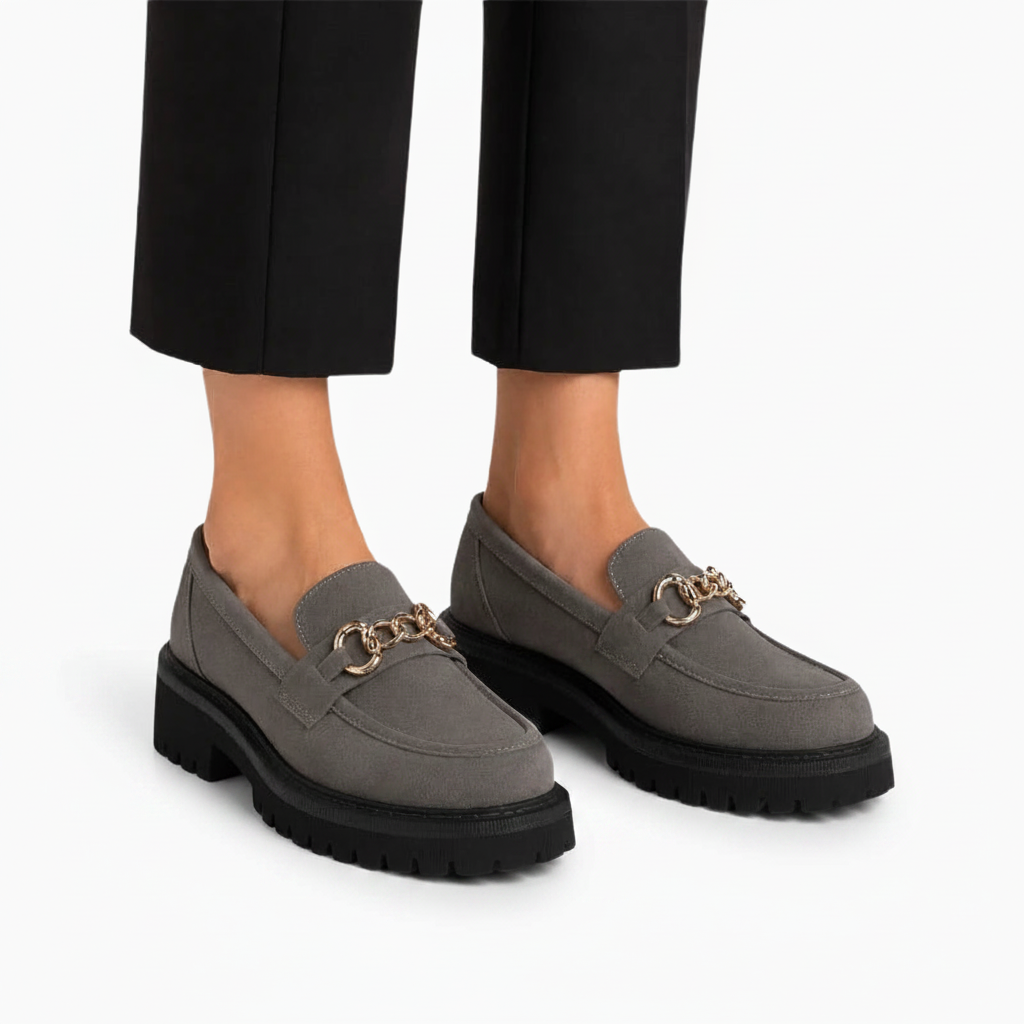 Pieds d'une femme portant les mocassins gris sous un pantalon fluide au bureau.