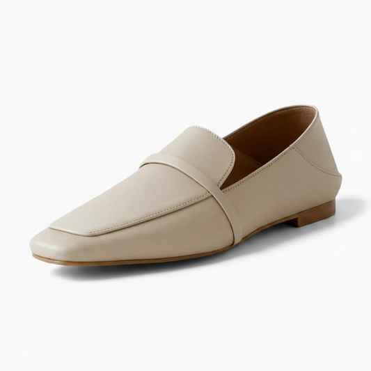 Mocassin crème pour femme en cuir souple, élégamment posé sur une surface lumineuse.