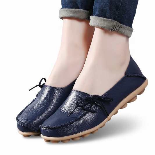 Pieds chaussés de mocassins bleu marine, associés à un pantalon de tailleur gris, pour un look professionnel.