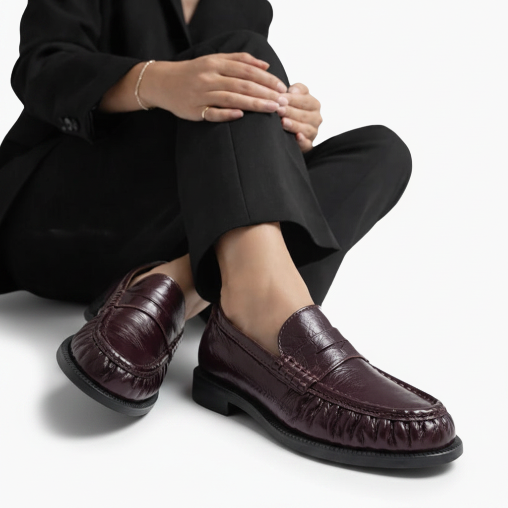 Texture rapprochée du cuir de vache bordeaux, révélant la qualité premium du matériau et son éclat subtil.