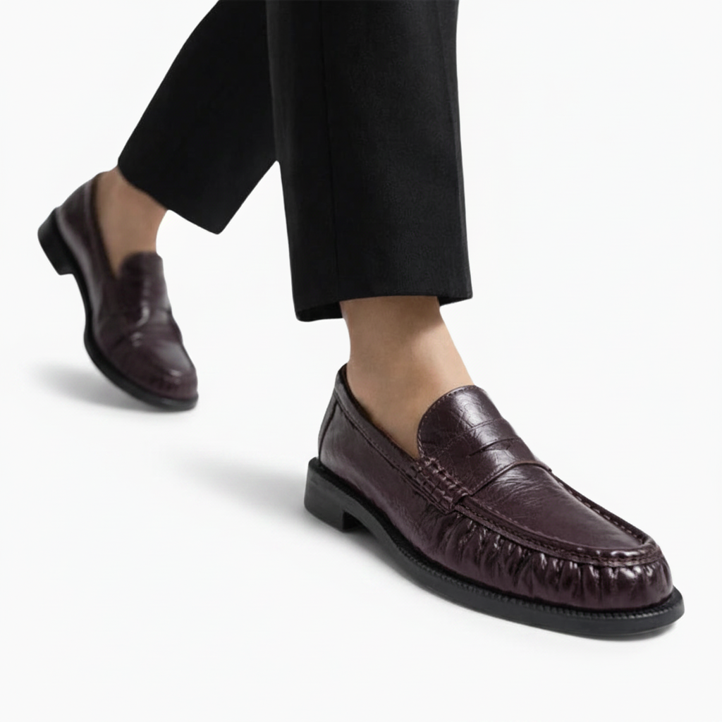 Femme marchant avec élégance, portant des mocassins bordeaux en cuir, soulignant leur confort et style intemporel.