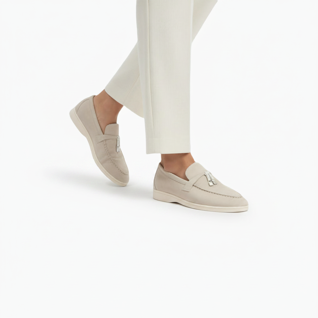 Détail des glands raffinés et des coutures délicates sur le mocassin en daim beige pour femme.