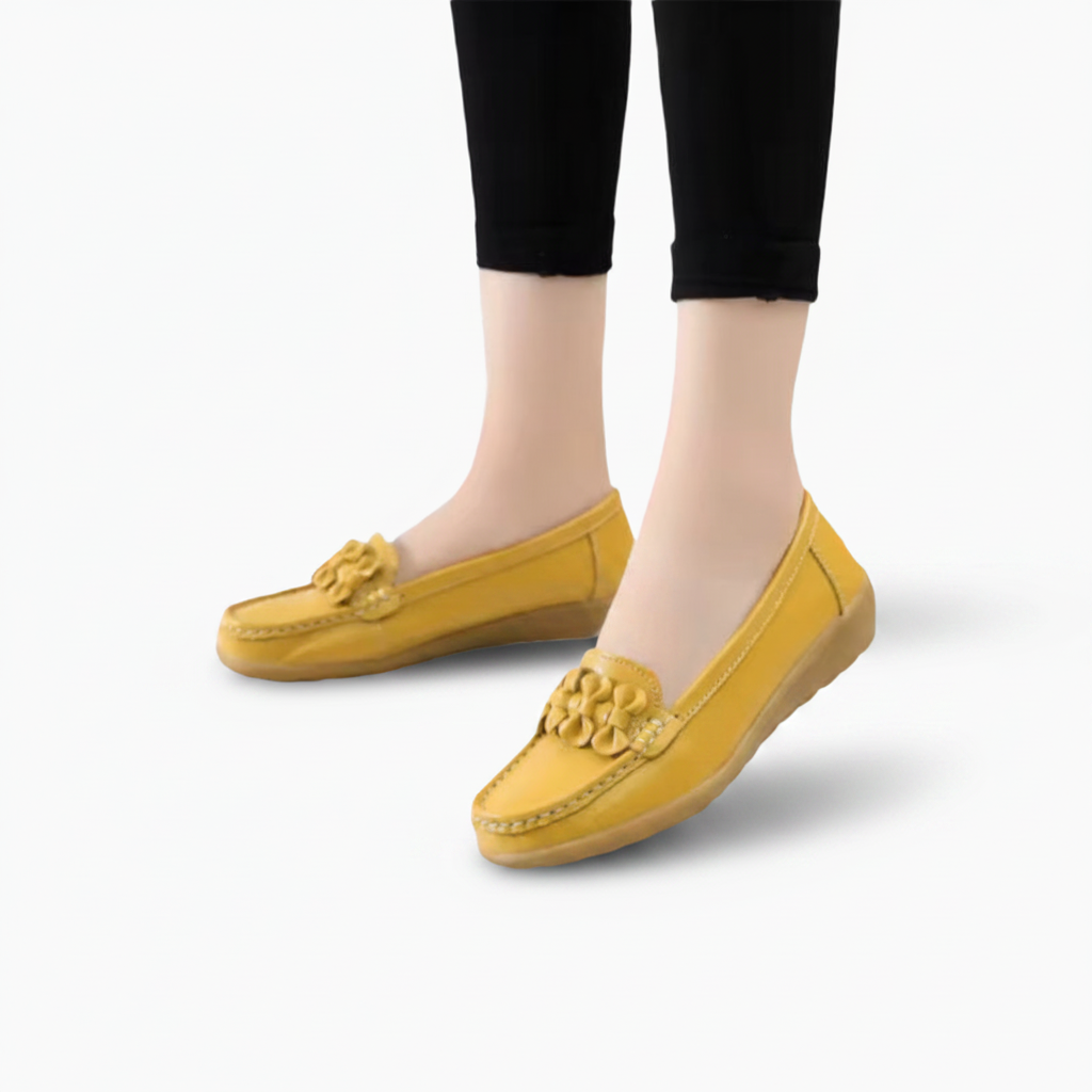 Pied de femme portant un élégant mocassin jaune en cuir, marchant avec confiance sur une terrasse ensoleillée.