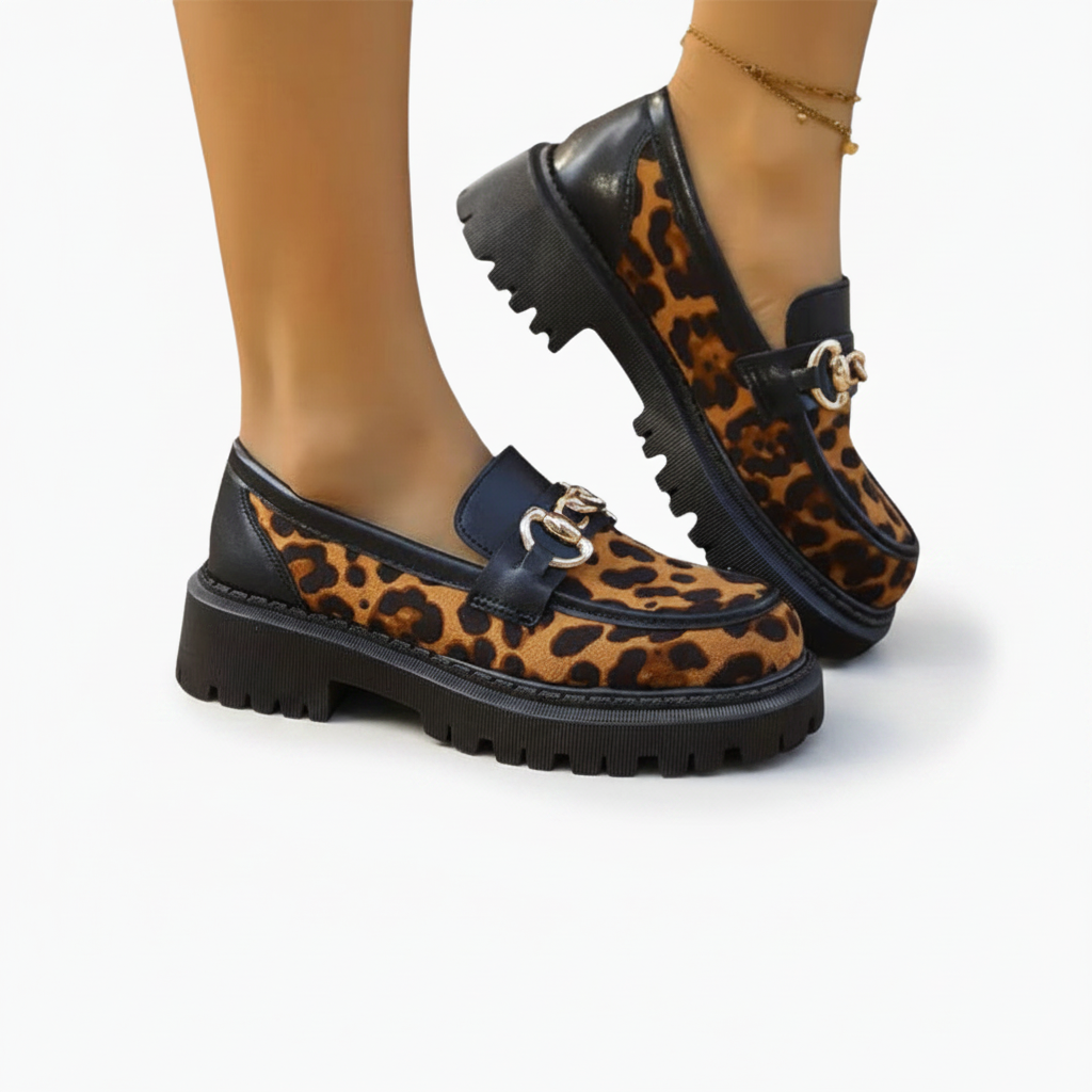 Pied chaussé d'un mocassin léopard, avec un pantalon élégant, pour un look moderne et raffiné.
