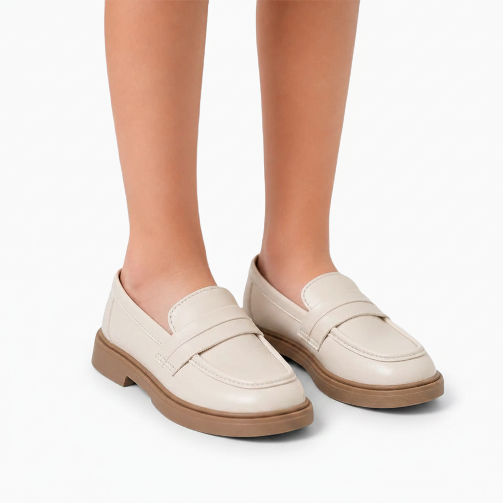 Fillette portant les mocassins compensés beige et marron avec un uniforme scolaire, look soigné.