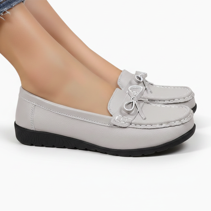 Gros plan sur le nœud papillon raffiné ornant l'empeigne du mocassin gris pour femme.