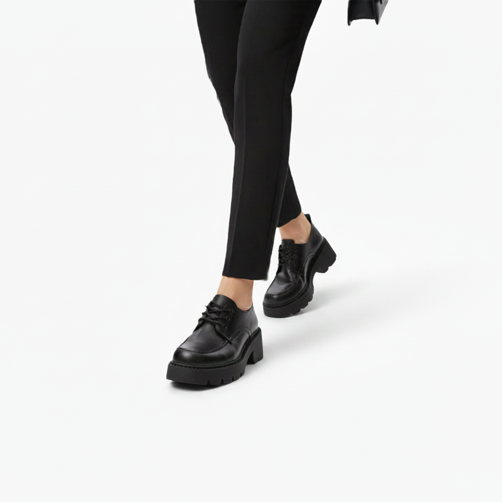 Paire de mocassins noirs à plateforme, présentés dans un studio, mettant en valeur leur design moderne.