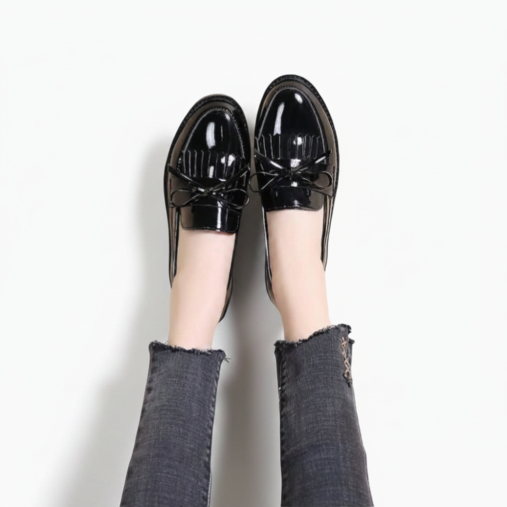 Gros plan sur la texture vernie du mocassin noir, reflétant la lumière avec subtilité.