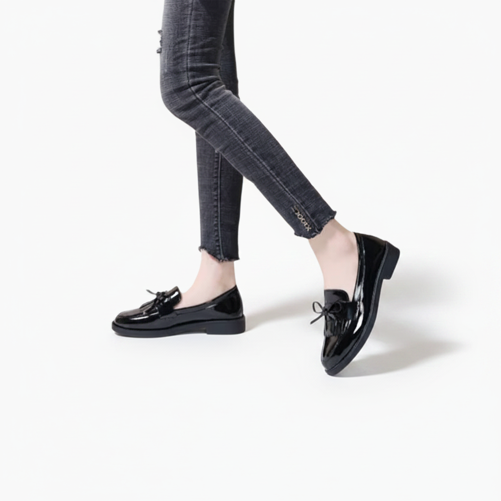 Mocassins noirs et brillants associés à un sac à main élégant, complétant un ensemble sophistiqué.