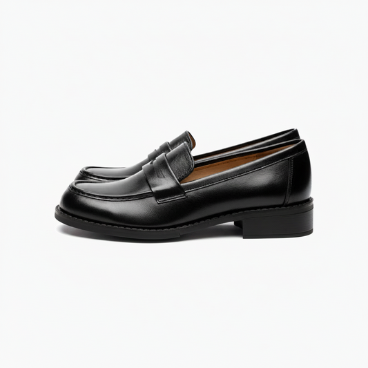 Gros plan sur le cuir verni noir brillant d'un mocassin féminin, reflétant la lumière.