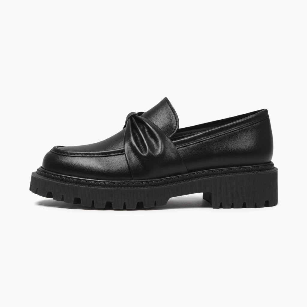 Détail raffiné du nœud féminin ornant le dessus du mocassin plateforme noir pour femme.