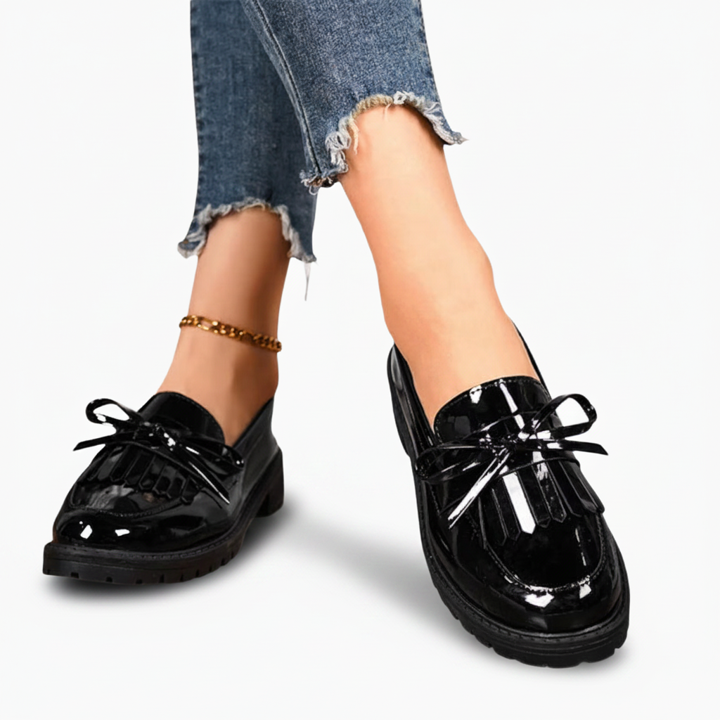 Gros plan sur le dessus d'un pied chaussé d'un mocassin plateforme en cuir noir, mettant en valeur la texture riche.