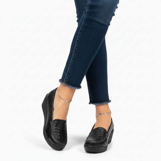 Mocassin plateforme en cuir noir porté par une femme, ajoutant une touche chic et contemporaine à sa tenue.